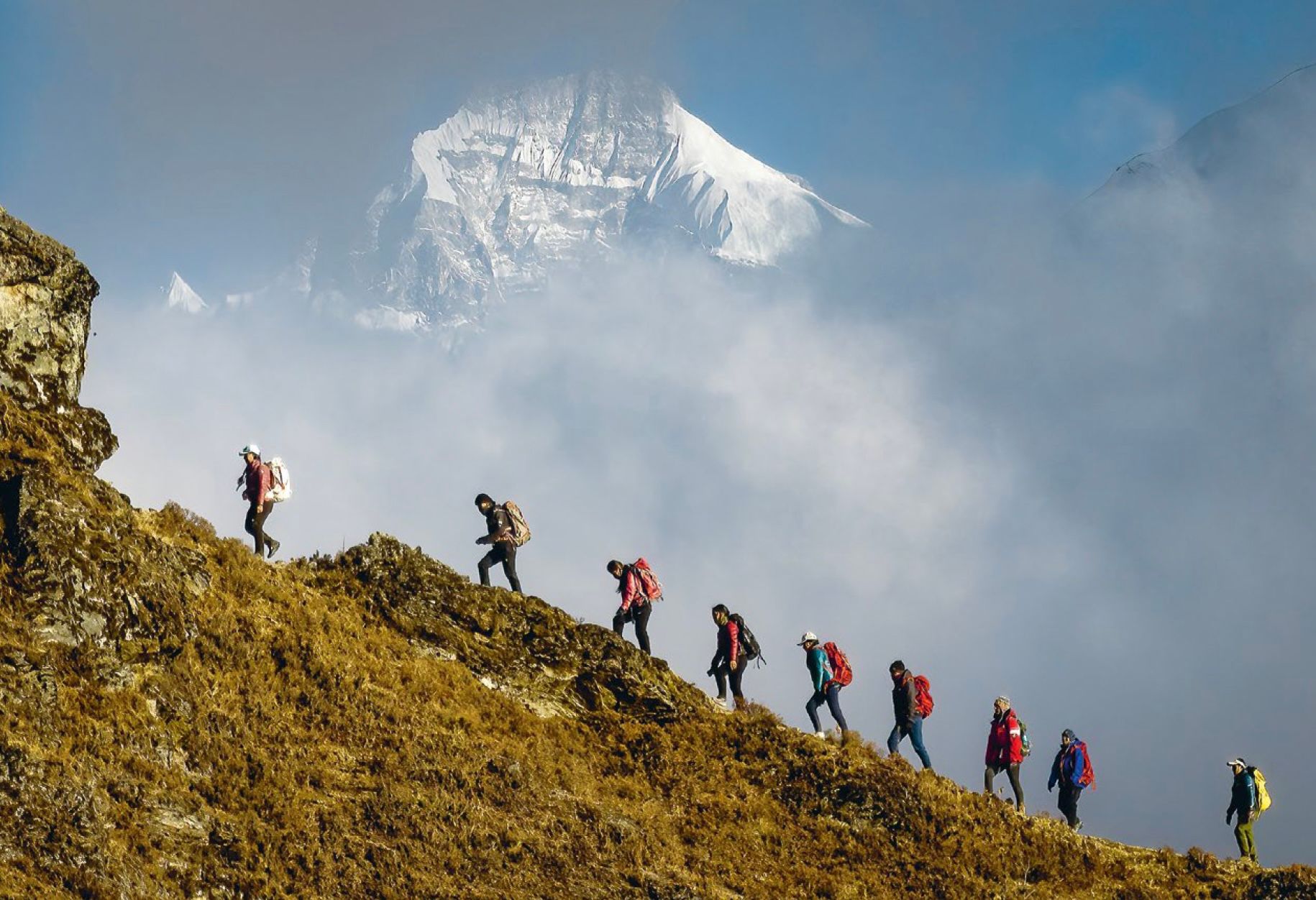 Dawa Yangzum Sherpa（左）正带领一群年轻女性登上山脊，白色的山峰为这些有抱负的登山者营造了鼓舞人心的背景。